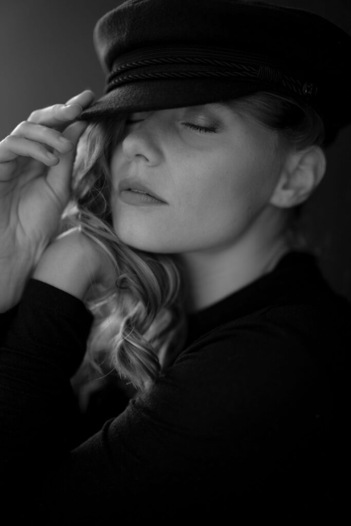 Schwarzweiss Fotografie einer Frau mit langen, blonden Haaren und einer Schiffermütze